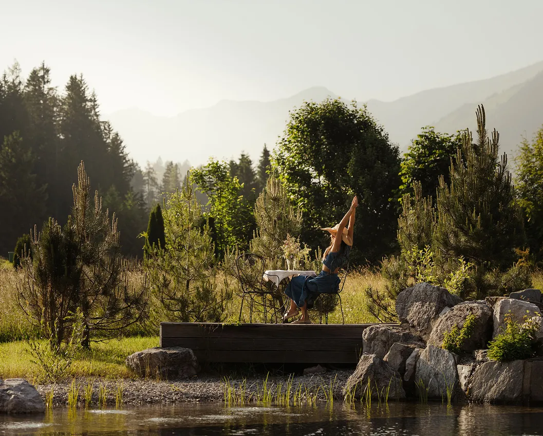 Woman relaxing with legs up on a wooden terrace overlooking the nature pond