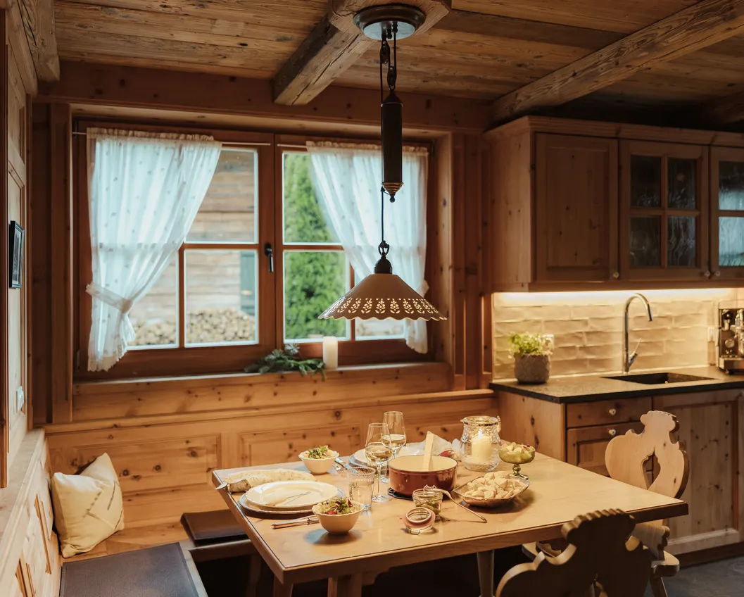 Traditional Tyrolean chalet dining room in solid wood with a set table and lace curtains