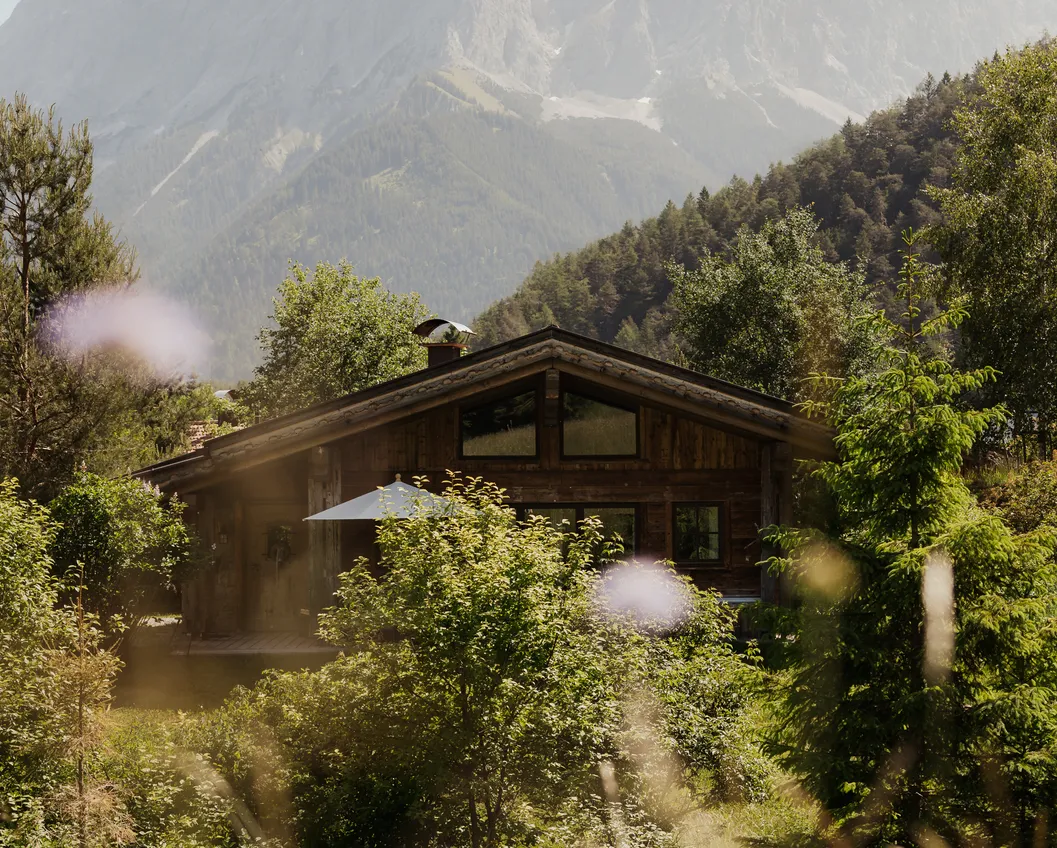 Wooden chalet in a summer wildflower meadow with the Zugspitze massif in the background