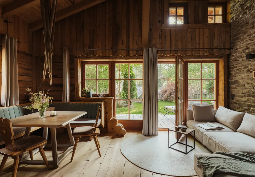 Spacious chalet living room with reclaimed wood walls, stone accents and nature pond terrace