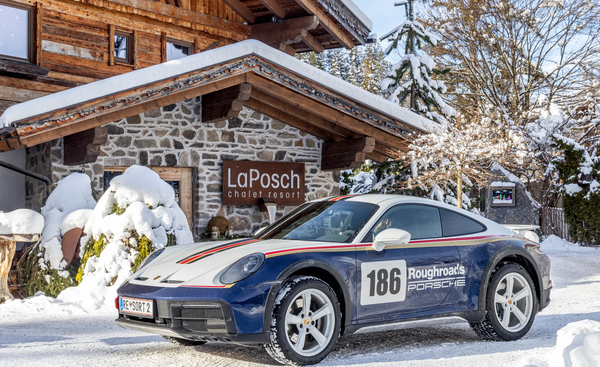 Porsche 911 Dakar mit Roughroads-Rally-Livery Nr. 186 vor dem LaPosch Chalet im Schnee