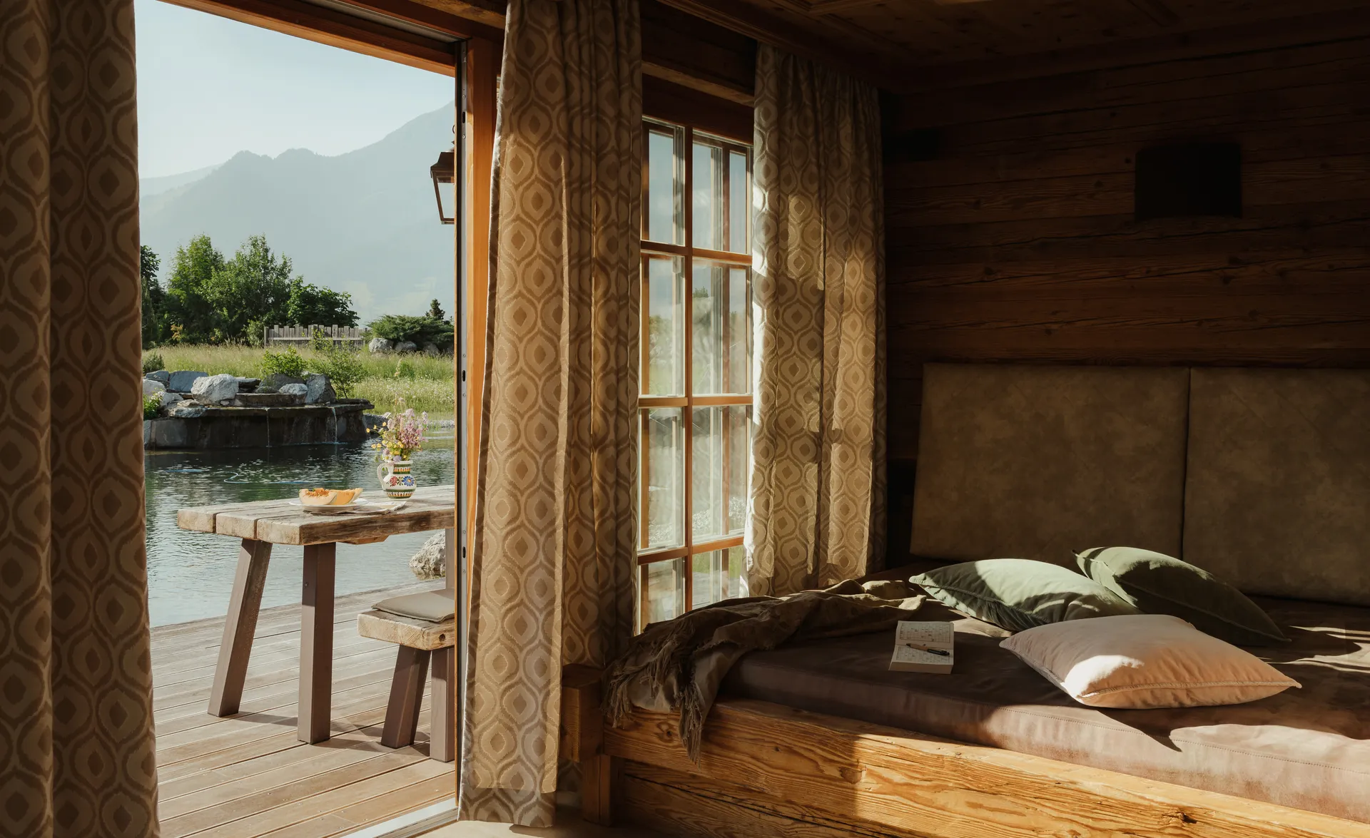 Gemütliche Chalet-Schlafkammer mit Holzbetteinbau und Terasse mit Teichblick