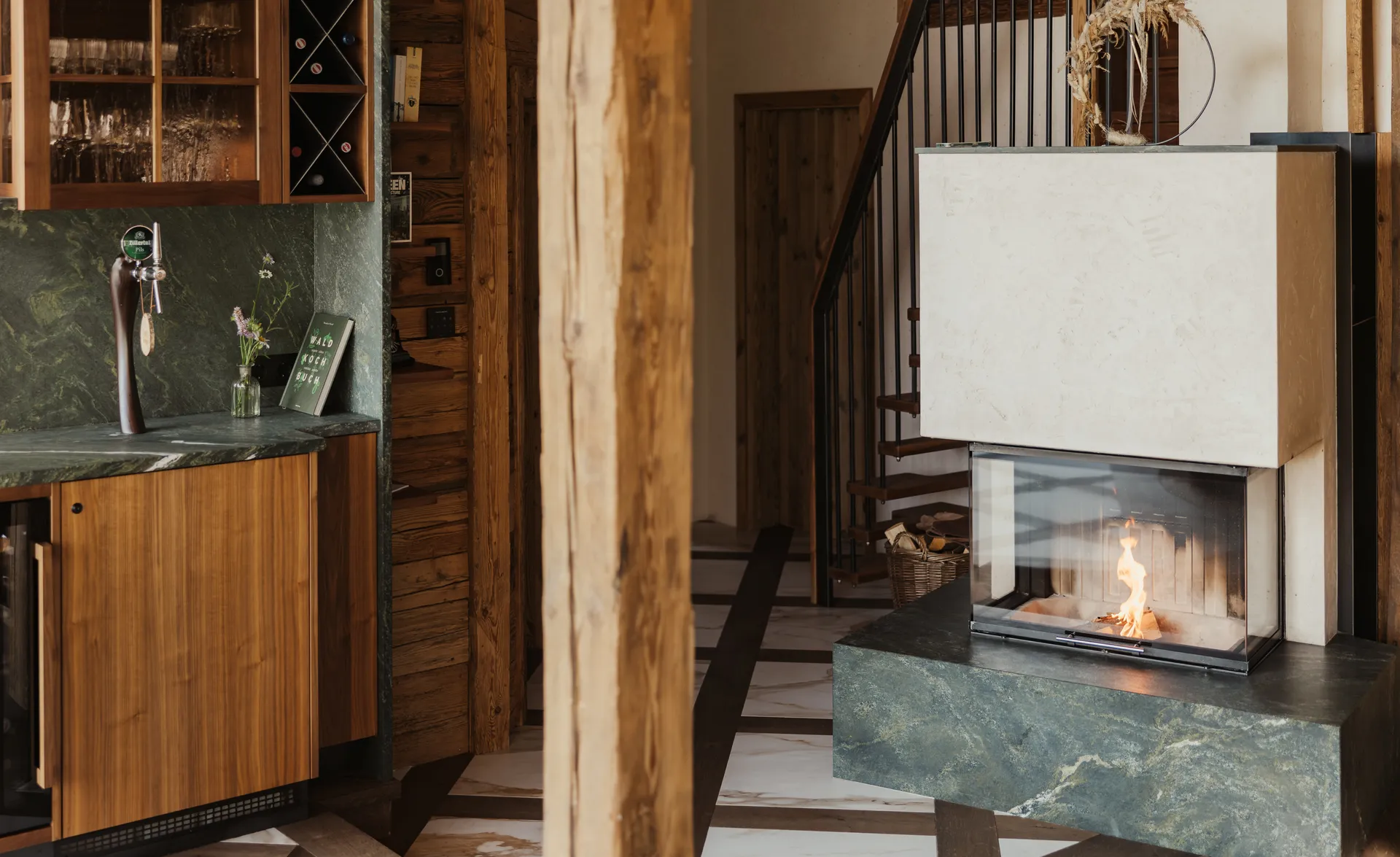 Chalet-Wohnbereich mit grünem Marmorfinish-Kamin, Naturholzbalken und Weinbar