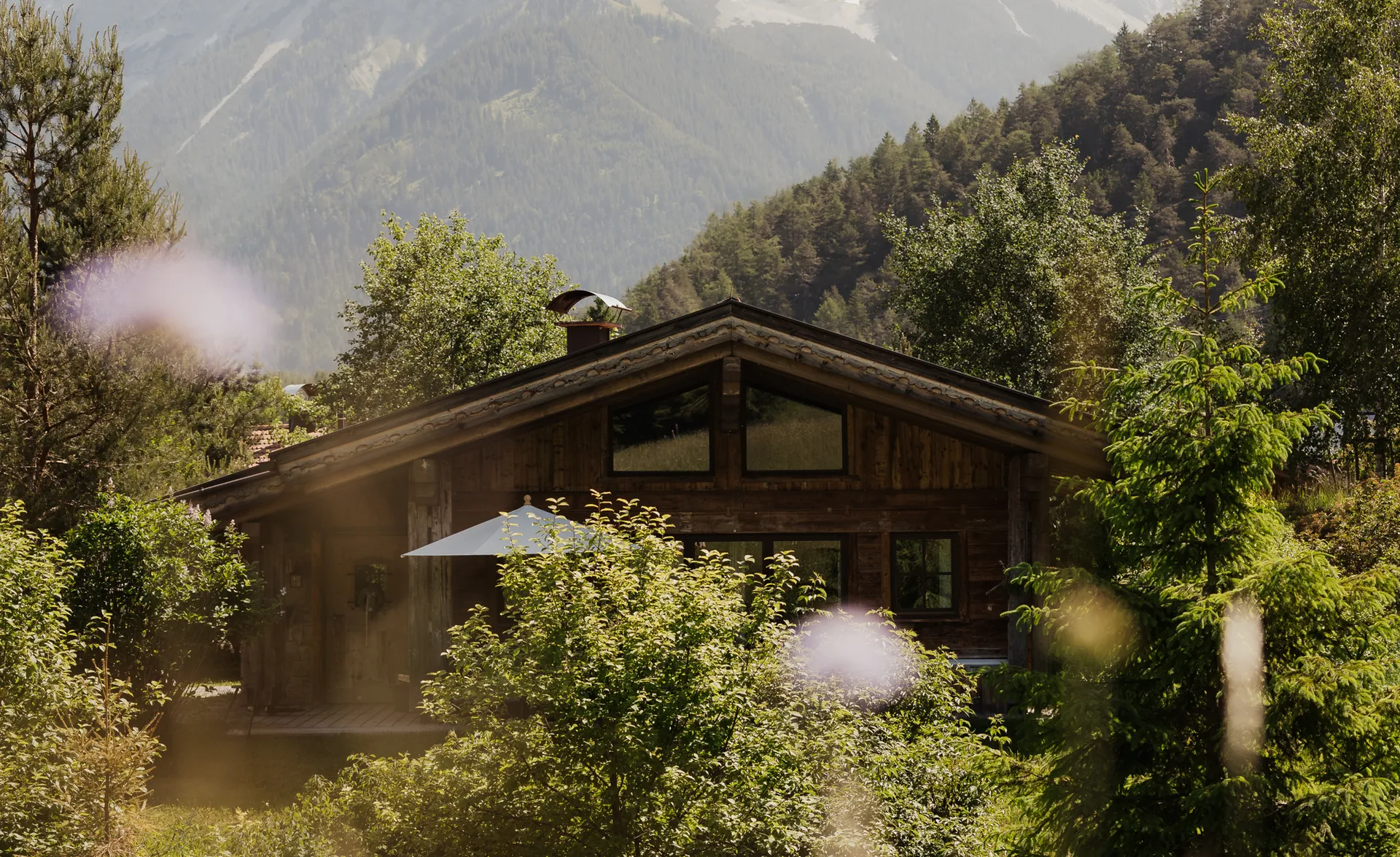 Holzchalet in sommerlicher Wildblumenwiese mit Zugspitze-Massiv im Hintergrund
