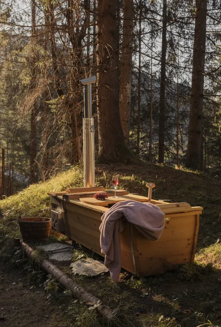 Outdoor-Holzbadebottich mit Kaminheizung im Waldregen der Tiroler Berge