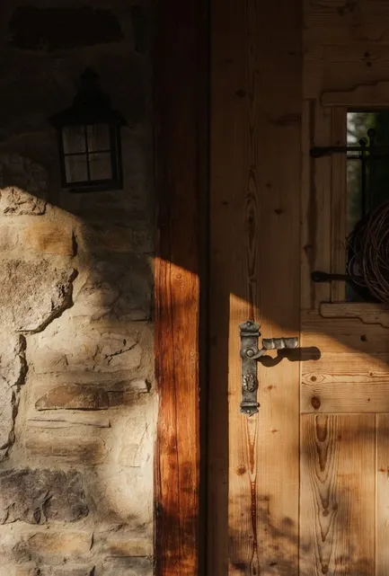 Rustikales Chalet-Schlafzimmer mit Altholzbalken, Steinakzentwand und Holzbett
