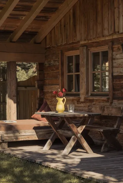 Überdachte Holzterasse mit Sonnenliege, Picknicktisch, Laterne und Gartenblick