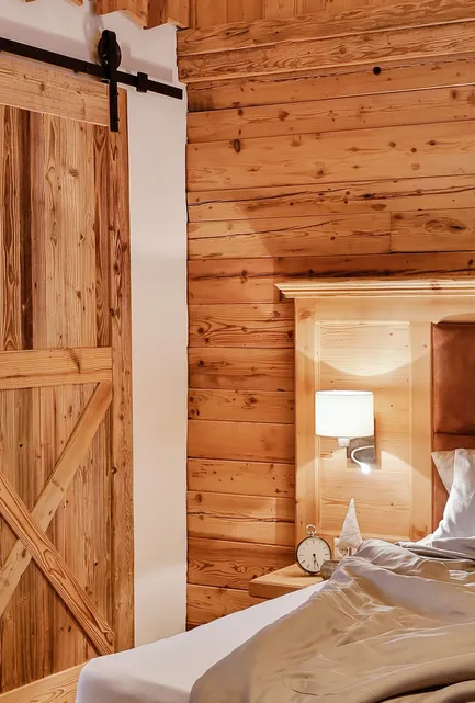 Chalet-Schlafzimmer mit Scheunentür-Schiebeelement, Holzrahmen-Bett und Herzdetail