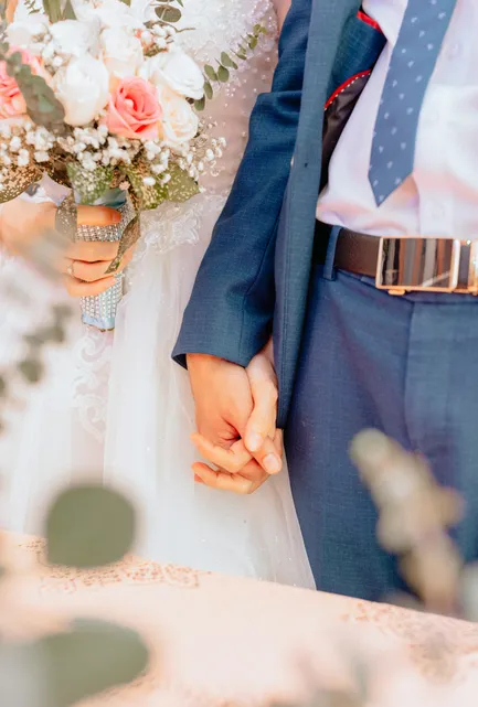 Brautpaar hält Hände — Brautkleid und rosé Brautstrauß mit Marineblauen Anzug