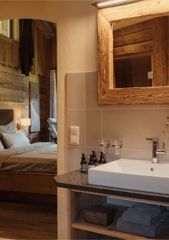 Badezimmer-Waschtisch mit quadratischem Waschbecken, Altholzspiegel und Holztür zum Zimmer