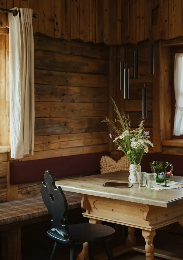 Tiroler Chalet-Essecke mit holzgetäfelten Wänden, Bankhocker und Kiefernholztisch