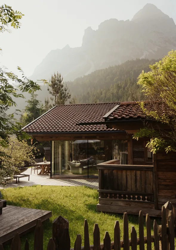 Goldstunden-Außenansicht des Holzchalets mit Loungebereich und Zugspitze-Silhouette