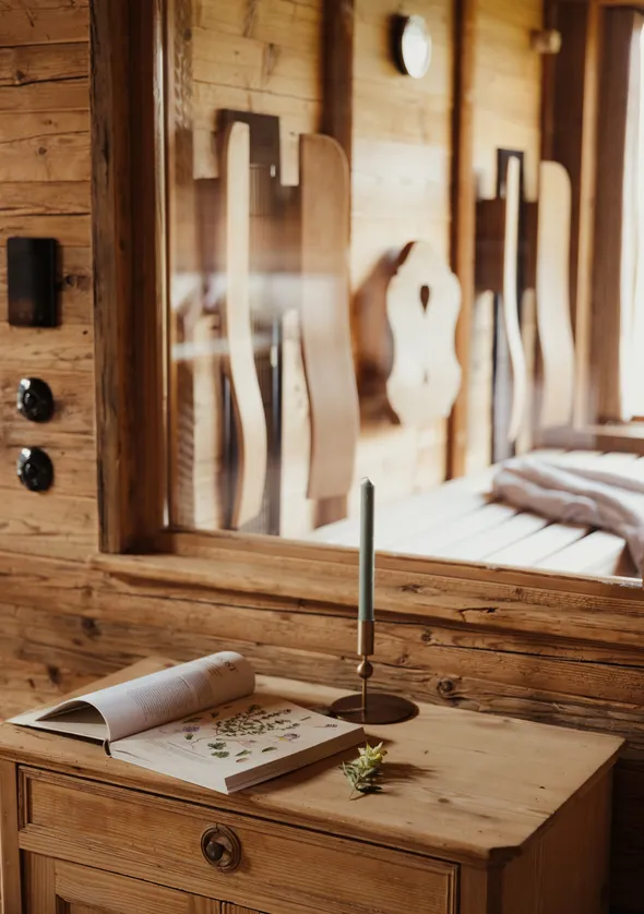 Rustikaler Holztisch in Sauna mit botanischem Buch, Bronzekerze und geschnitzten Holzlehnen