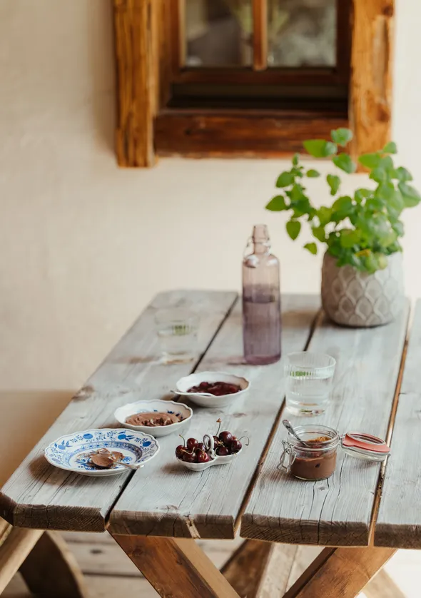 Rustikaler Chalet-Frühstückstisch mit Kirschen, Schokoaufstrich und frischen Kräutern
