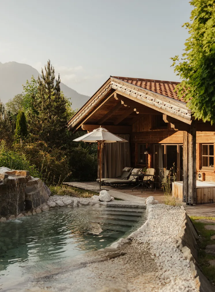Holzchalet mit Natursee-Badeteich, Sonnendeck und Bergkulisse im Morgendunst