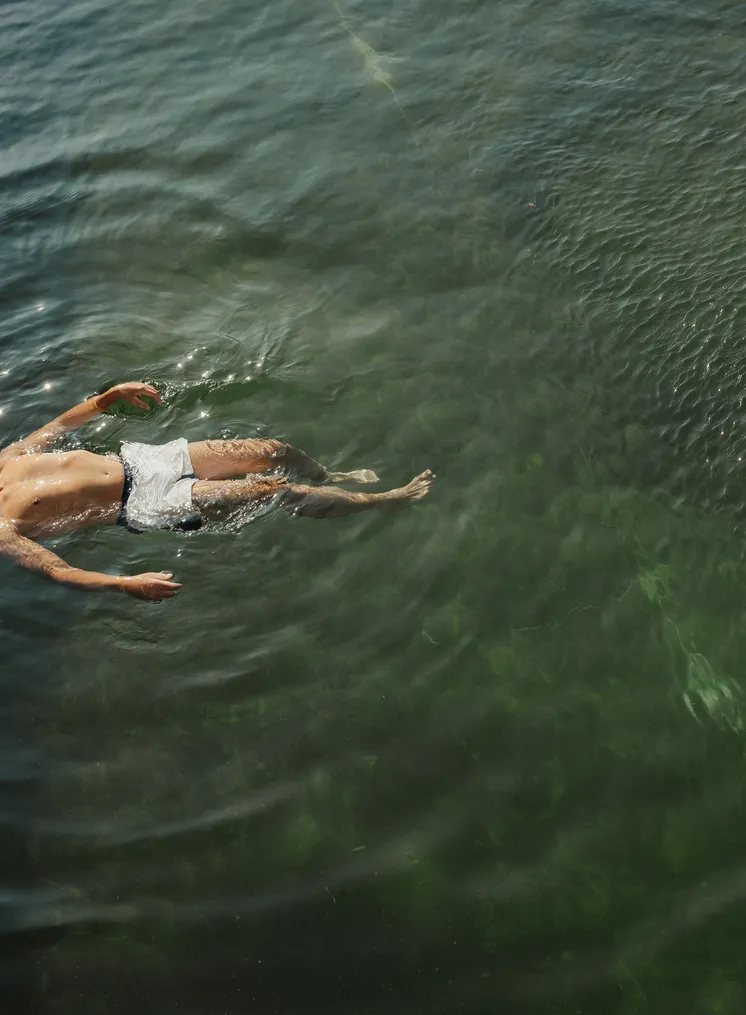 Person schwimmt entspannt auf dem Rücken im ruhigen See — totale Erholung