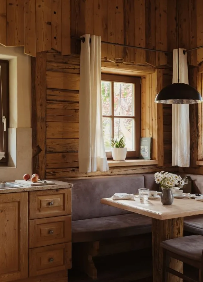 Chalet-Küchenzeile mit Zirbenholz-Einbauküche, Eckbank, Holztisch und schwarzer Pendellampe
