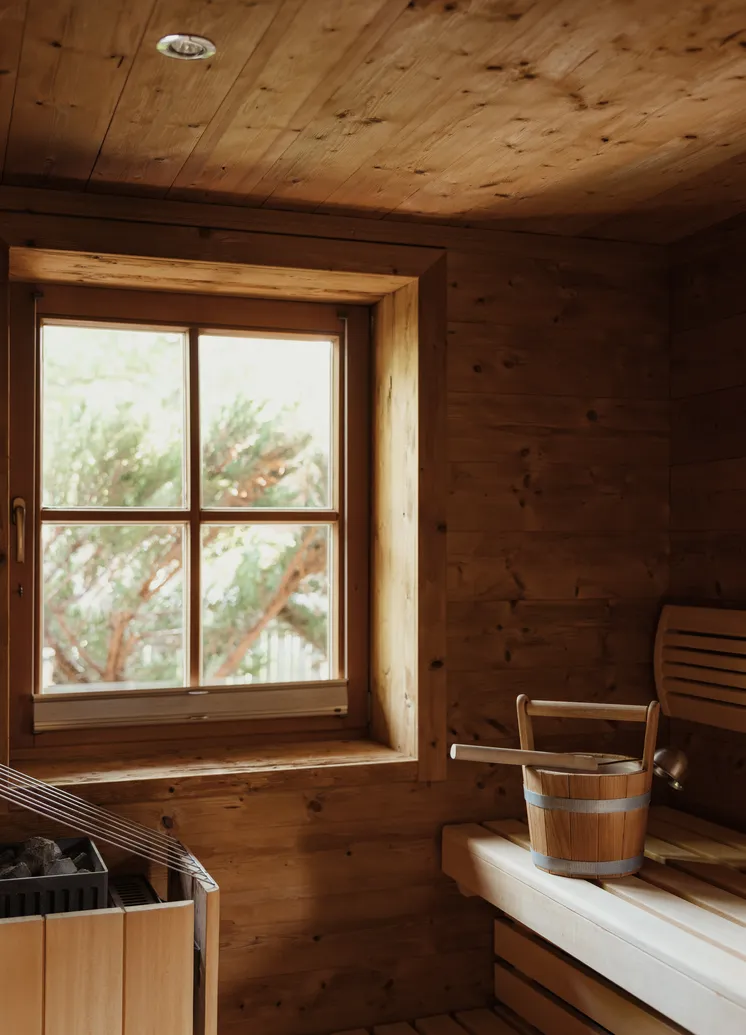 Klassische Holzsauna mit Steinofen, Wassereimer und Ladle sowie Grünblick