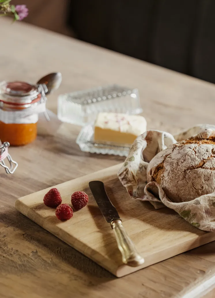 Rustikales Frühstücks-Stillleben mit Brot, Marmelade, Butter und Wildblumen